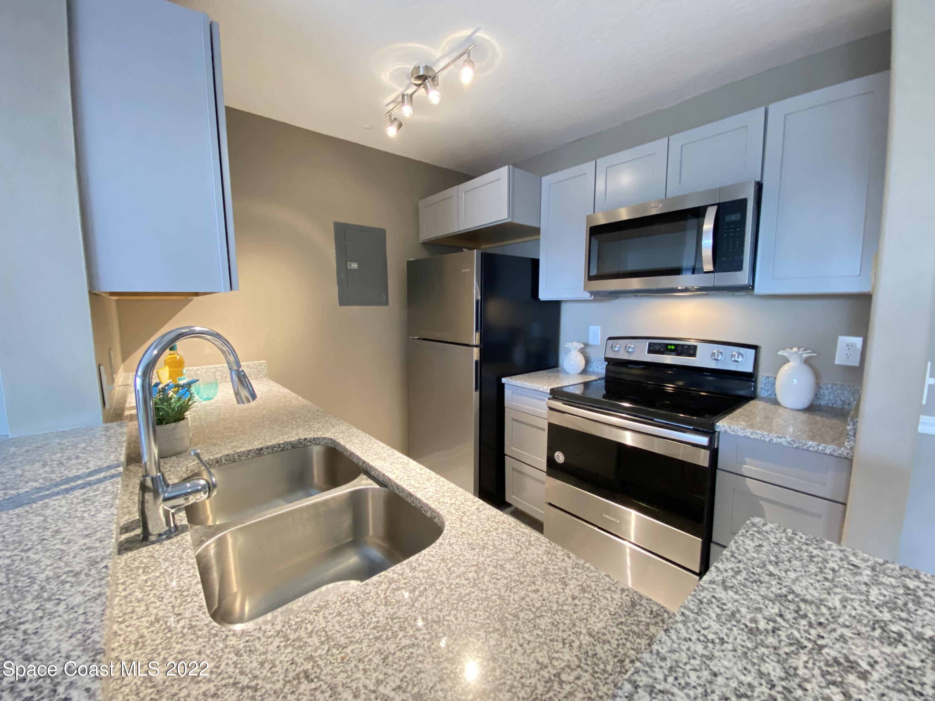 7667 North Wickham Road, Unit 418 Melbourne, FL 32940 - Photo 8 of 36 a kitchen with stainless steel appliances granite countertop a sink and a stove