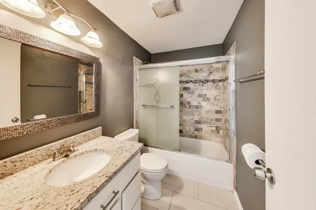 a bathroom with a granite countertop sink toilet and shower
