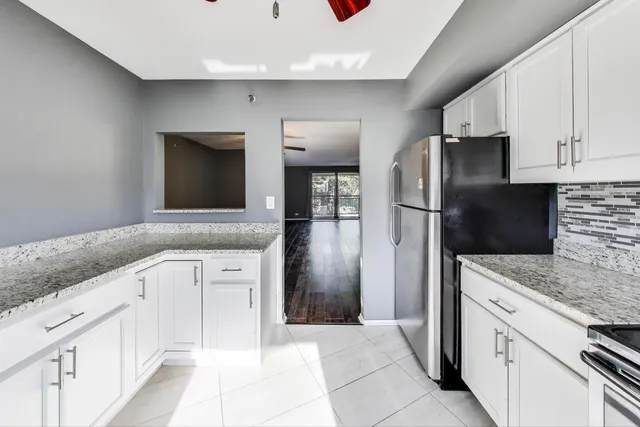 a kitchen with granite countertop white cabinets and stainless steel appliances