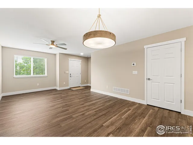 a view of an empty room with window and wooden floor