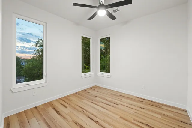 a view of empty room with wooden floor and fan