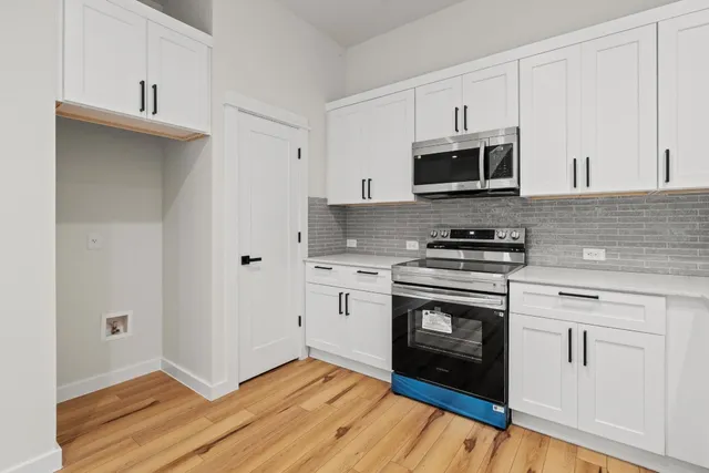 a kitchen with cabinets stainless steel appliances and wooden floor