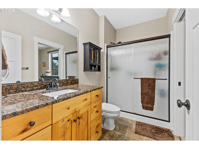 a bathroom with a granite countertop sink mirror vanity and toilet