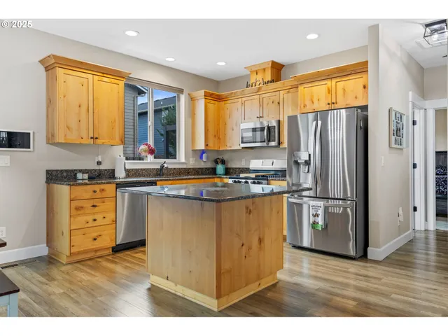 a kitchen with granite countertop a refrigerator cabinets and wooden floor