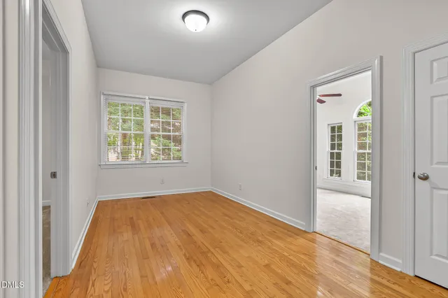 an empty room with a window and a fan