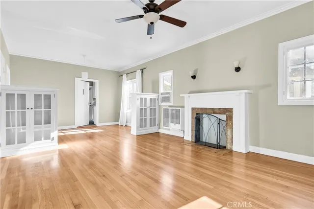 a view of an empty room with window and wooden floor