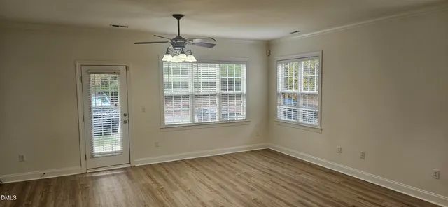 a view of an empty room with wooden floor and a window