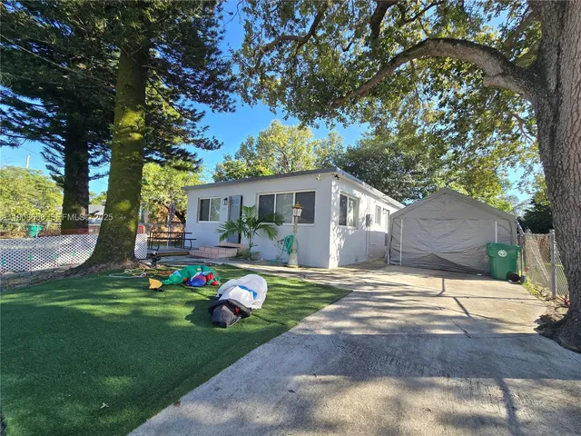 a front view of white house with a garden and trees