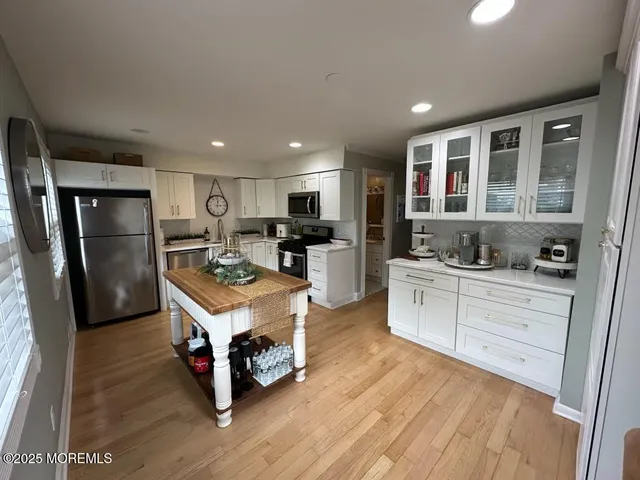 a kitchen with kitchen island a stove a refrigerator a sink and cabinets