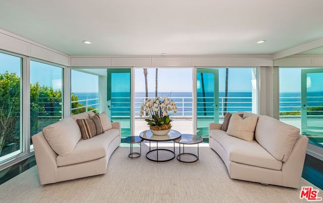 a living room with furniture and floor to ceiling windows