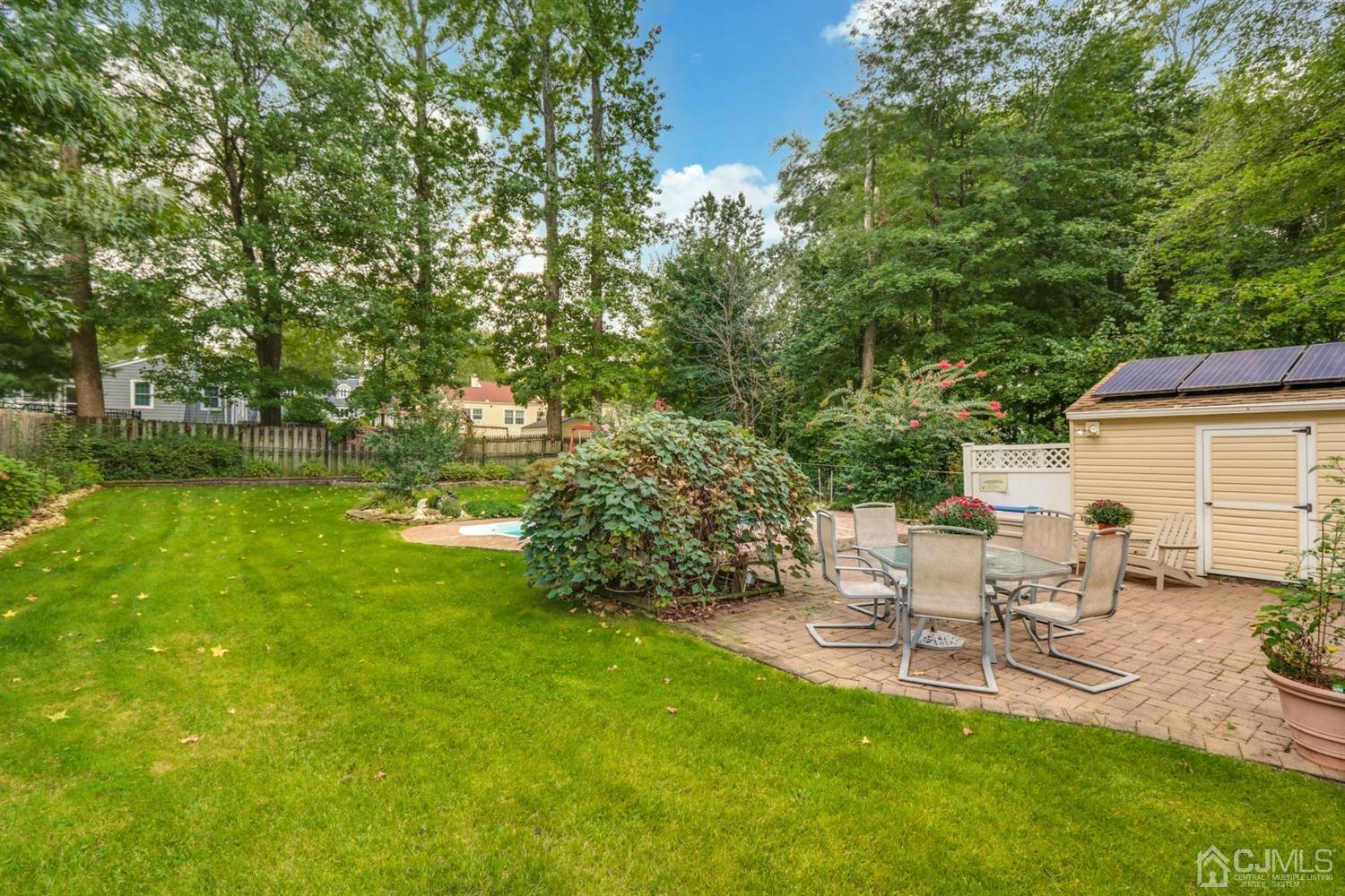 217 Oxford Road Edison, NJ 08820 - Photo 24 of 27 a view of a backyard with table and chairs and potted plants and large trees