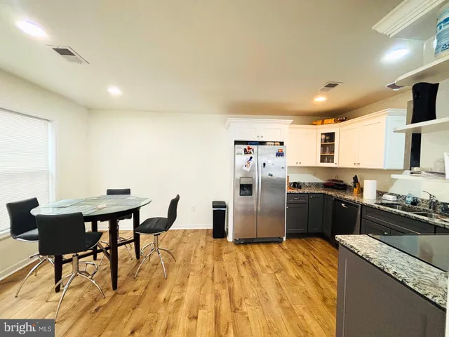 a kitchen with stainless steel appliances kitchen island granite countertop a refrigerator a stove a sink dishwasher with a dining table and chairs with wooden floor