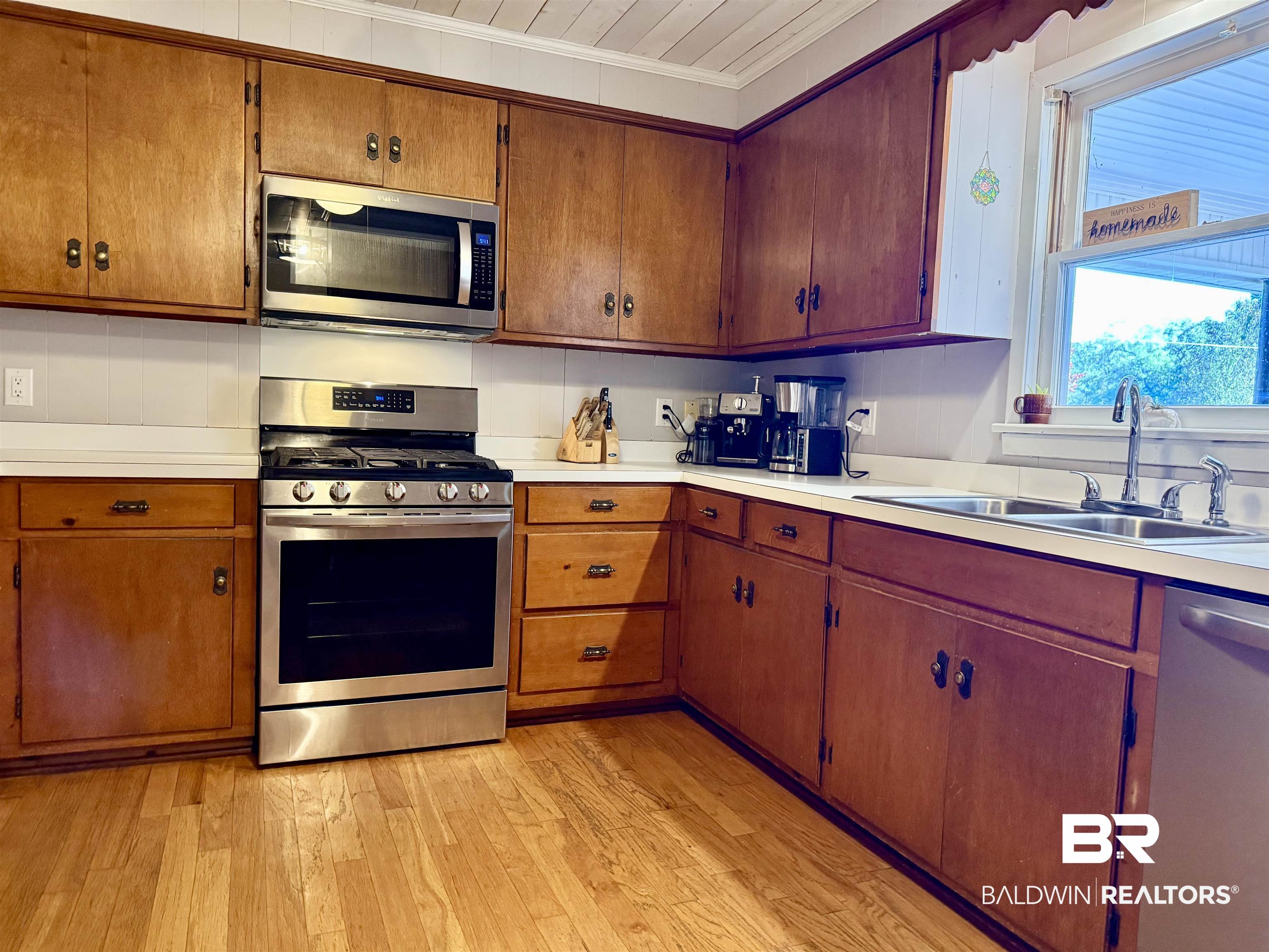 2785 Appleton Road Brewton, AL 36426 - Photo 10 of 28 Kitchen with appliances with stainless steel finishes, light countertops, light wood finished floors, ornamental molding, and brown cabinetry