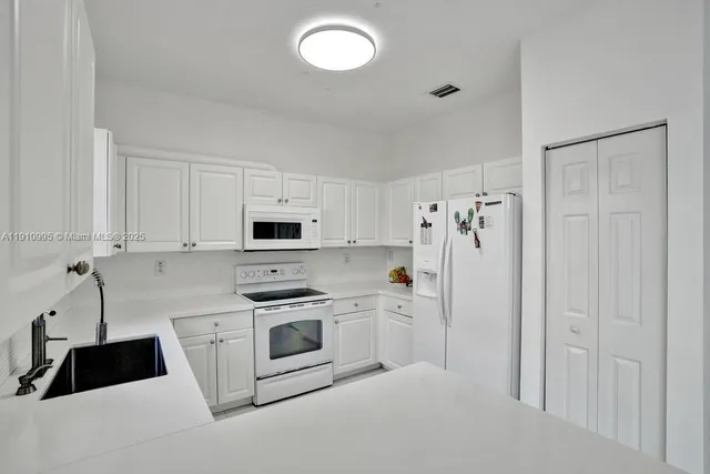a kitchen with a sink white cabinets and stainless steel appliances