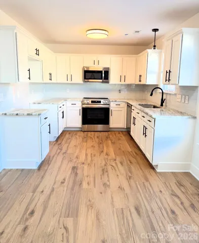 a view of an empty room with wooden floor and a fireplace