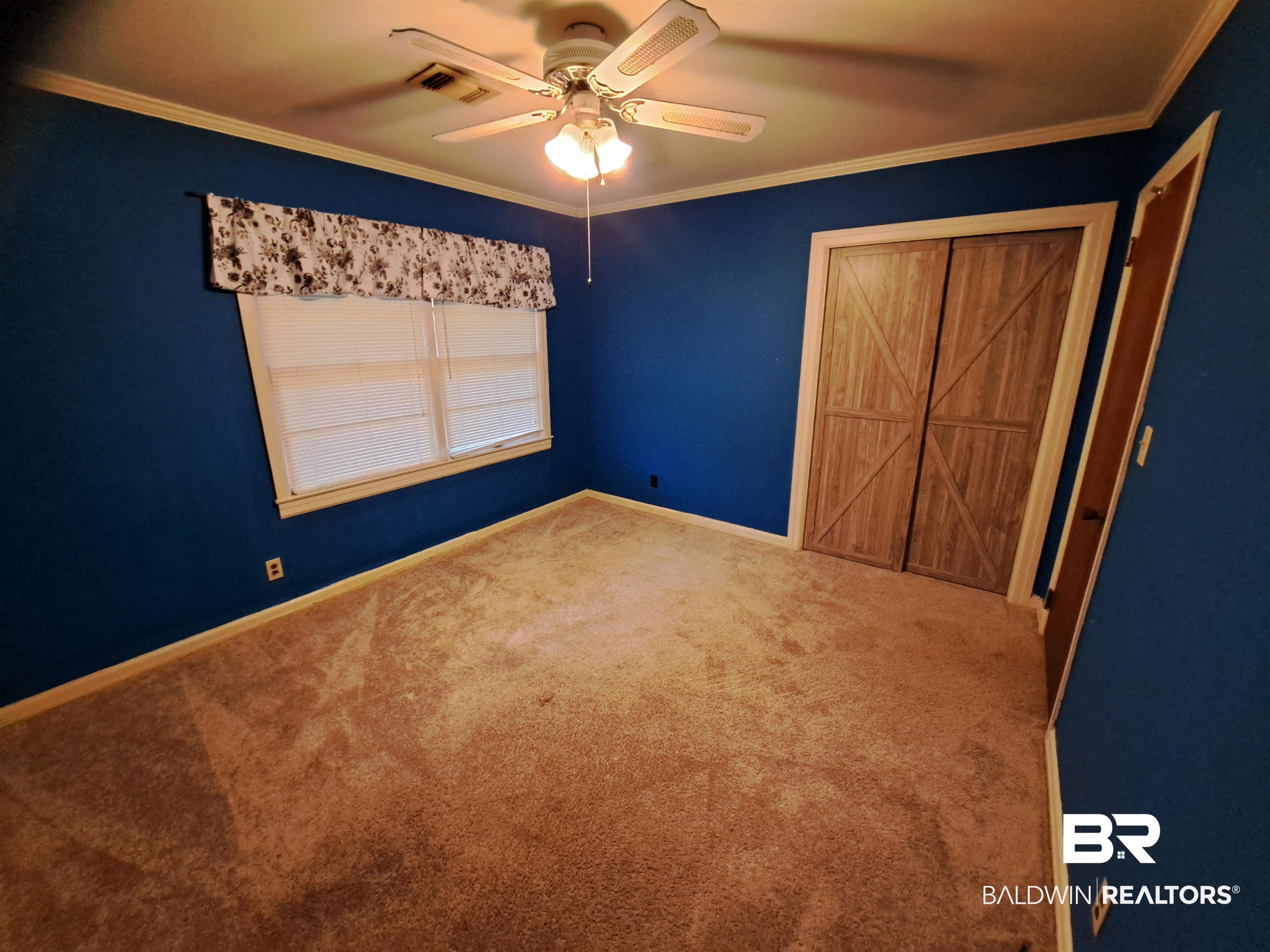 249 Newton Parkway Evergreen, AL 36401 - Photo 19 of 28 Unfurnished bedroom with ornamental molding, a ceiling fan, carpet flooring, and a closet