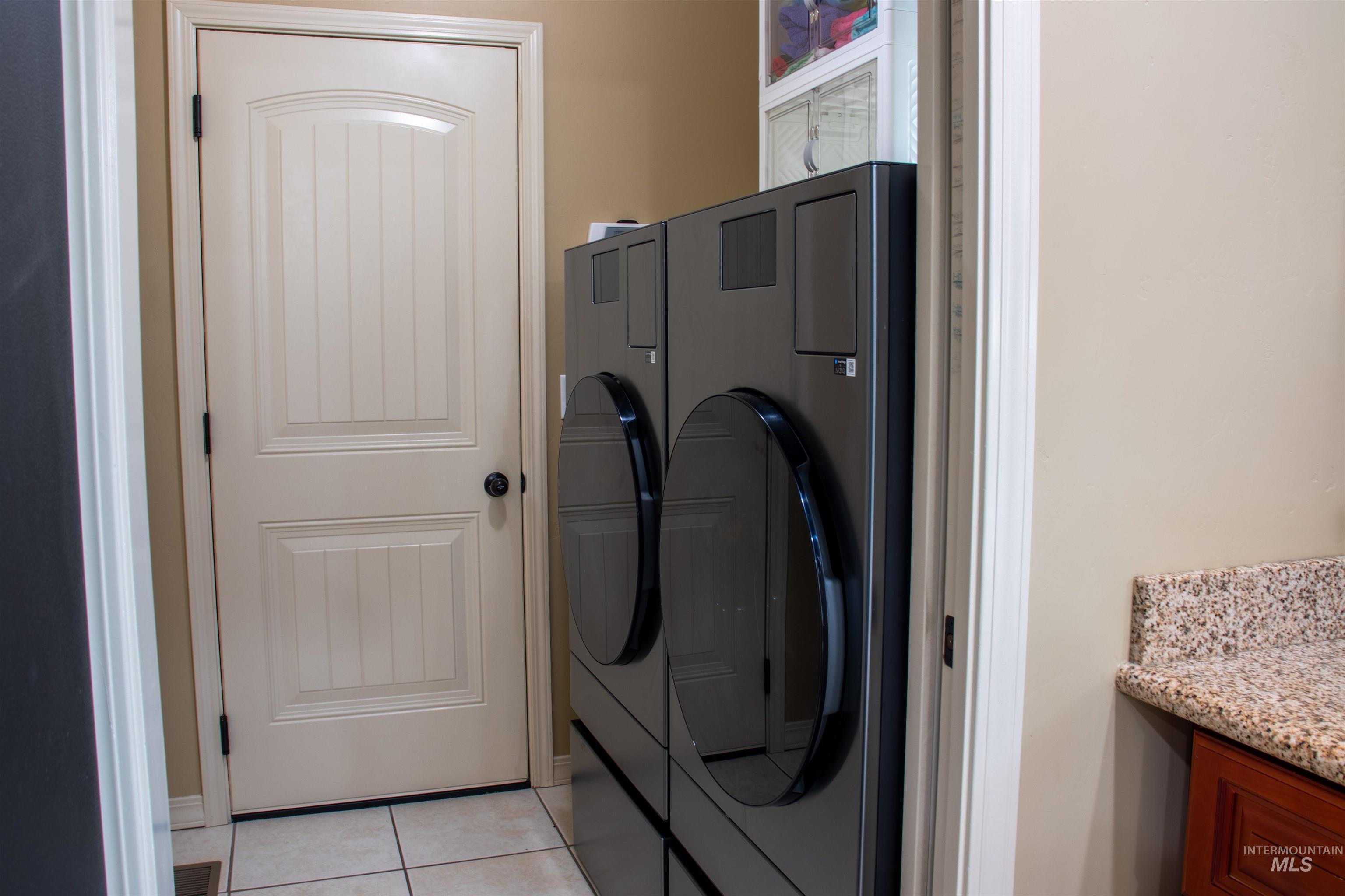 2000 M Street Heyburn, ID 83336 - Photo 11 of 15 Laundry area featuring tile flooring, a paneled door, and a built-in countertop with a flecked surface