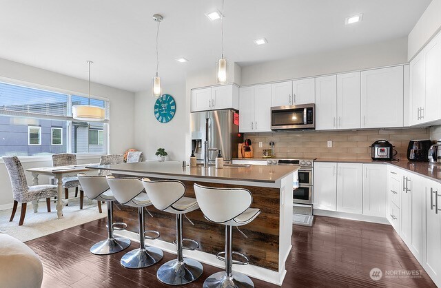 1325 Seattle Hill Road, Unit C2 Bothell, WA 98012 - Photo 7 of 26 a kitchen with stainless steel appliances granite countertop a sink a stove a refrigerator a dining table and chairs with wooden floor