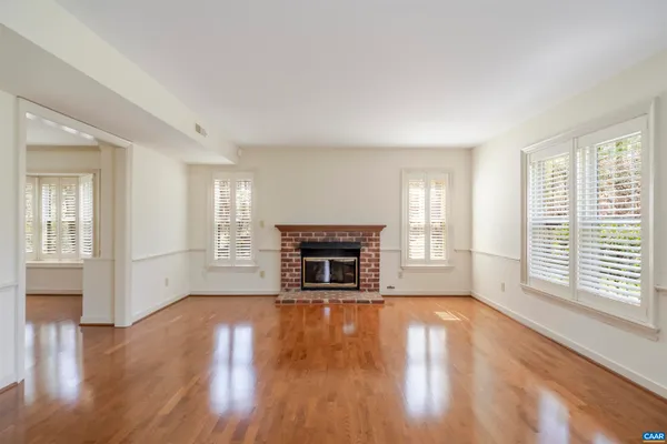 an empty room with wooden floor chandelier fan and windows