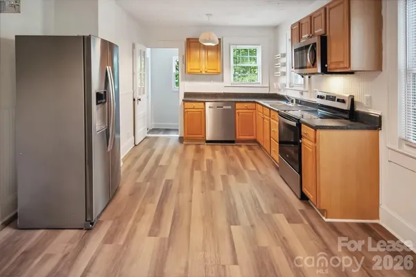 a kitchen with granite countertop a stove top oven a sink dishwasher and a refrigerator with wooden floor