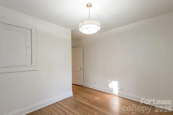 a view of a hallway with wooden floor and a bathroom