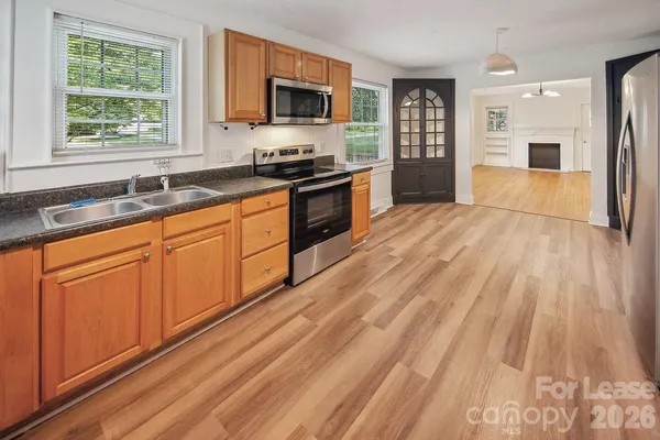 a kitchen with stainless steel appliances granite countertop a refrigerator a sink dishwasher a stove with wooden cabinets and floor