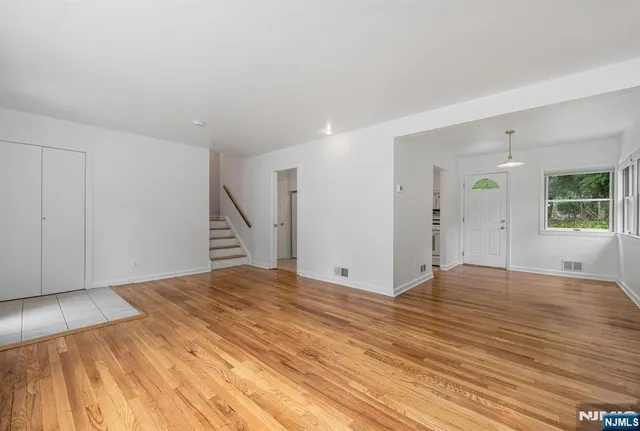 a view of an empty room with wooden floor and stairs