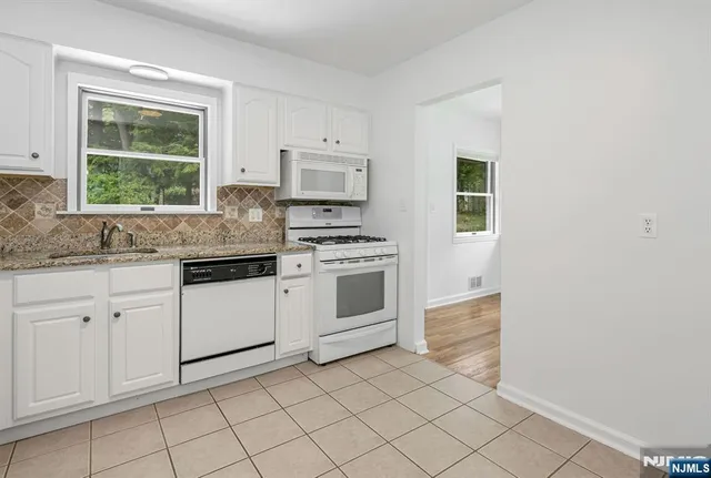 a kitchen with white cabinets appliances and a window