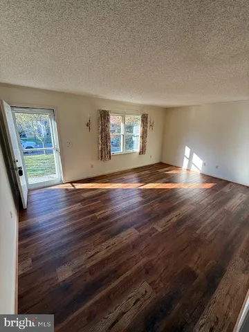 a view of empty room with window and wooden floor