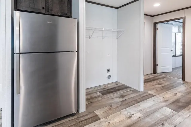 a view of a refrigerator in kitchen and an empty room