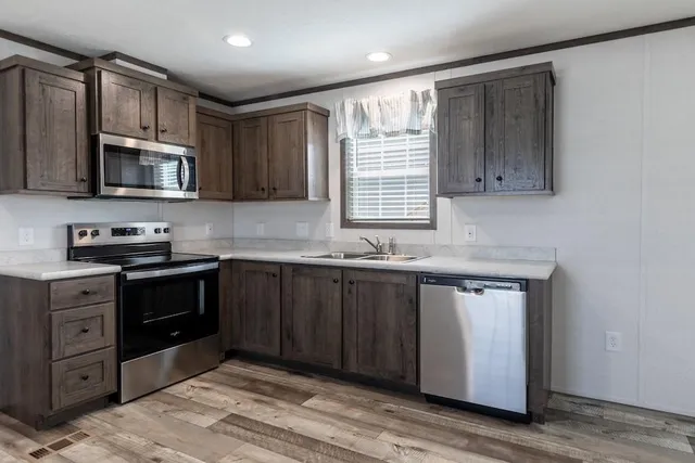 a kitchen with stainless steel appliances granite countertop a stove a sink and a microwave