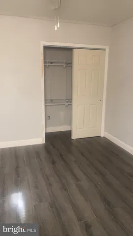 a view of an empty room with wooden floor and closet