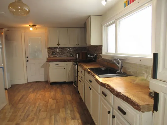 a kitchen with granite countertop a sink a counter space appliances and cabinets