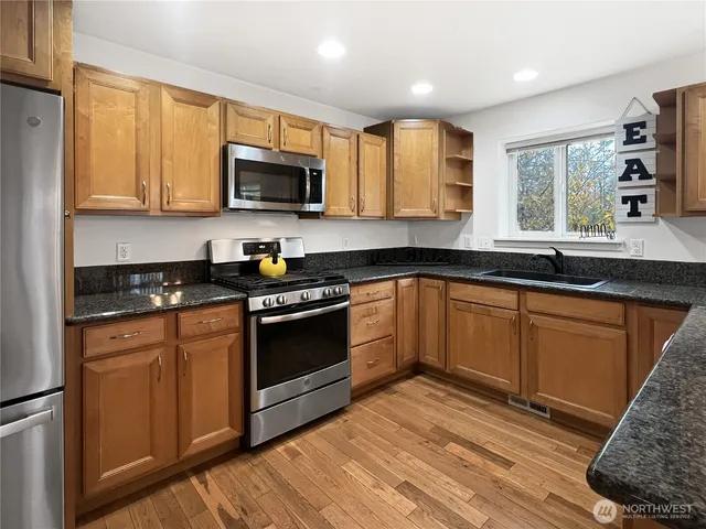 a kitchen with stainless steel appliances granite countertop a stove a sink and a microwave