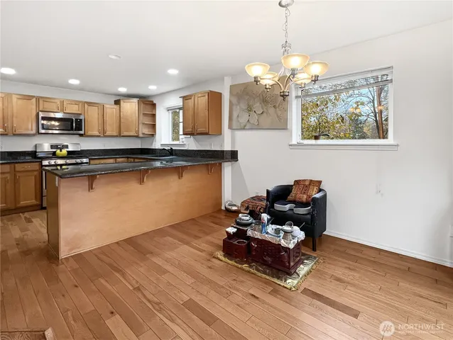 a kitchen with stainless steel appliances granite countertop a stove a sink dishwasher and a wooden floor