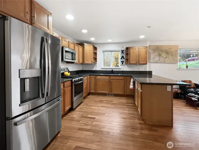 a kitchen with stainless steel appliances granite countertop a refrigerator a sink dishwasher a stove top oven and a refrigerator