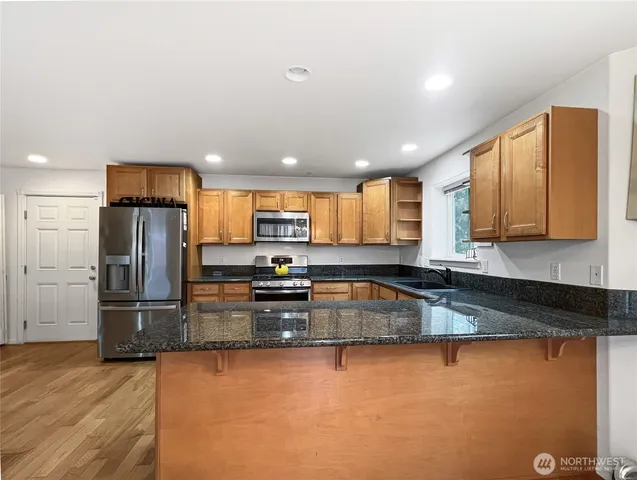 a kitchen with stainless steel appliances granite countertop a refrigerator a stove top oven a sink and dishwasher