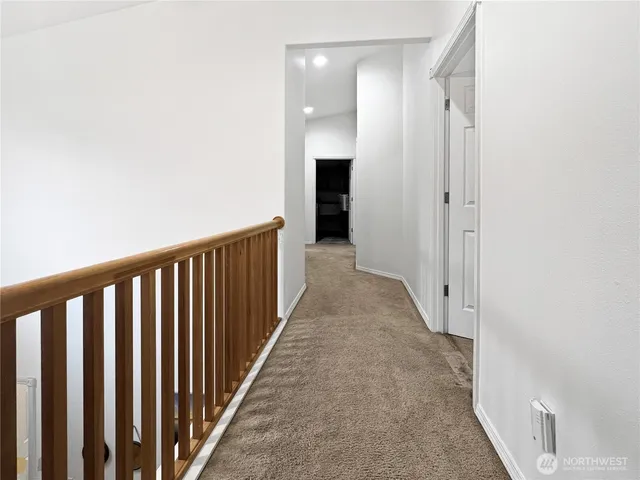 a view of a hallway with wooden floor and a bathroom