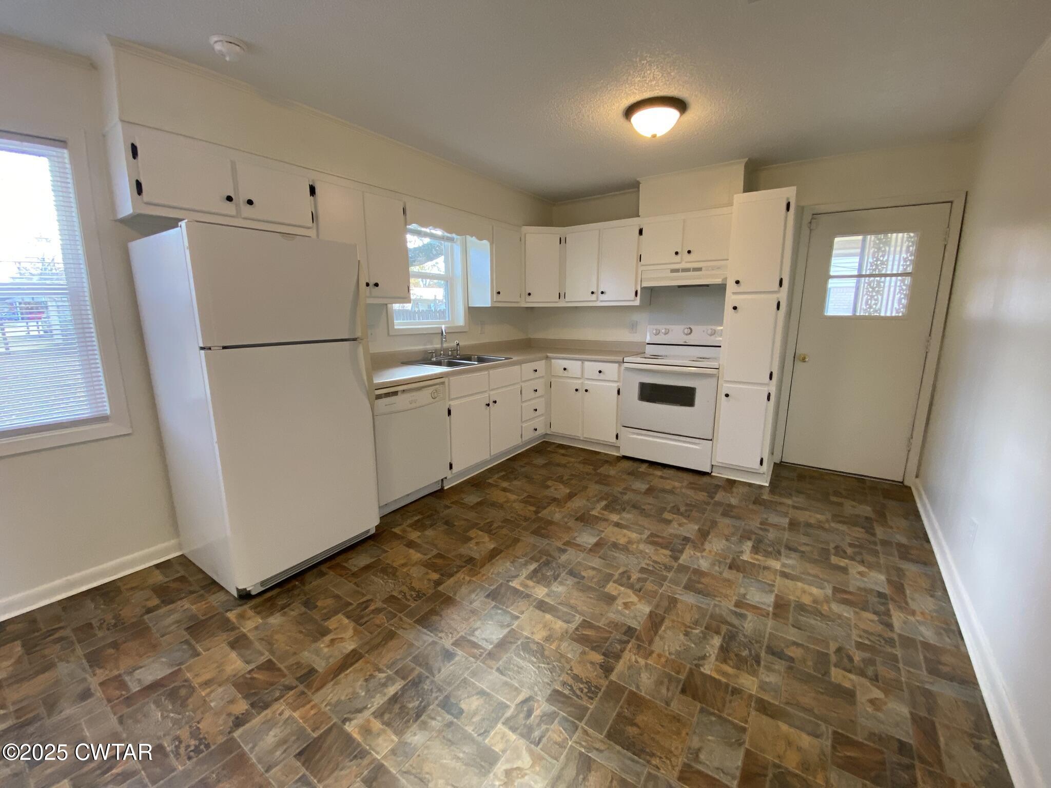 234 Tulip Street Henderson, TN 38340 - Photo 7 of 14 a kitchen with granite countertop a refrigerator a sink dishwasher a stove a refrigerator and white cabinets