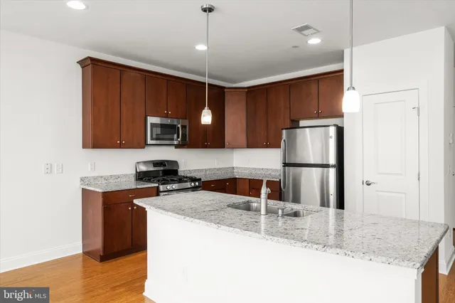 a kitchen with granite countertop a refrigerator a sink a stove a microwave and wooden cabinets