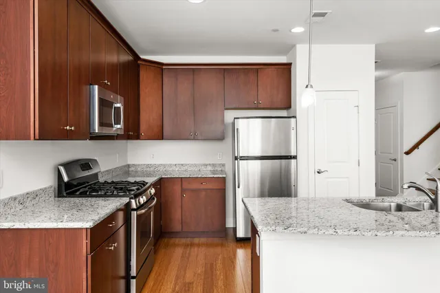 a kitchen with stainless steel appliances granite countertop a sink stove and refrigerator