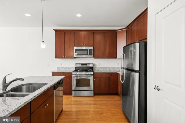 a kitchen with stainless steel appliances granite countertop a refrigerator stove and sink