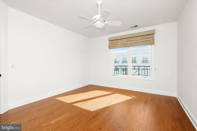 an empty room with a window and a ceiling fan