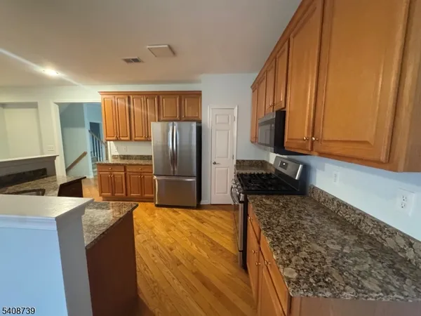 a kitchen with stainless steel appliances granite countertop a refrigerator and a stove top oven