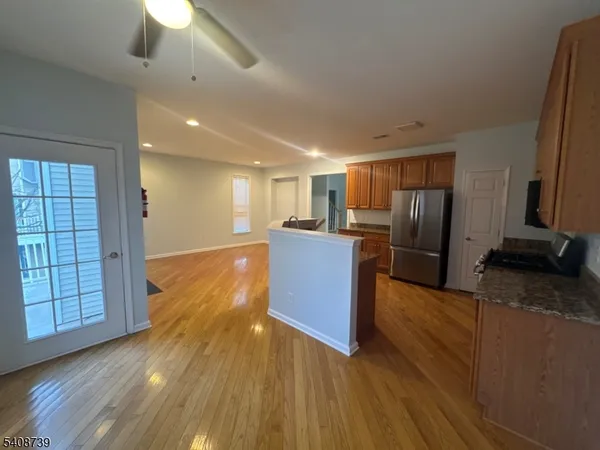 a kitchen with stainless steel appliances granite countertop a refrigerator a stove and a wooden floors