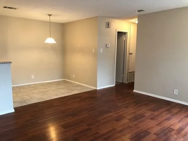 an empty room with wooden floor and bathroom view
