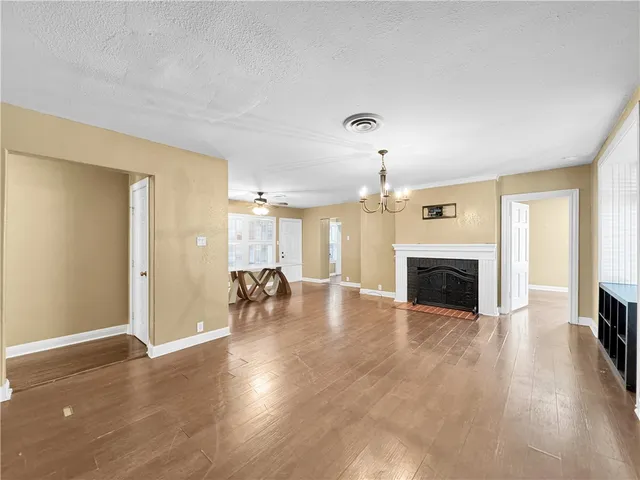 an empty room with fireplace wooden floor and windows