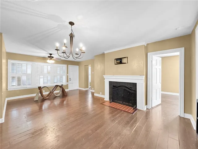an empty room with fireplace chandelier and wooden floor