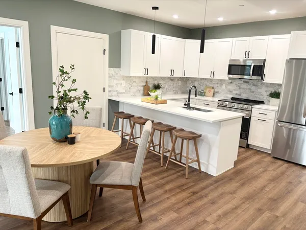 a kitchen with stainless steel appliances granite countertop a dining table chairs refrigerator sink and cabinets