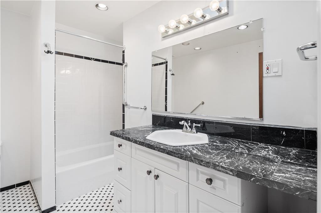 457 44th Street Brooklyn, NY 11220 - Photo 12 of 16 a bathroom with a granite countertop sink a mirror a vanity and a bathtub